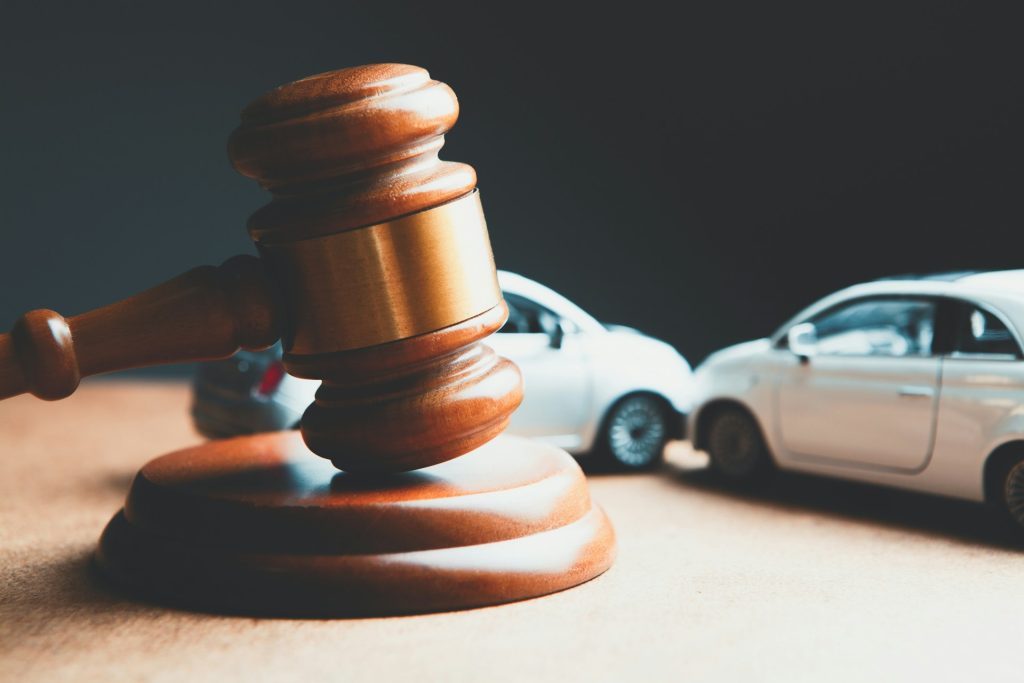 A wooden gavel sitting in front of toy cars simulating a traffic accident