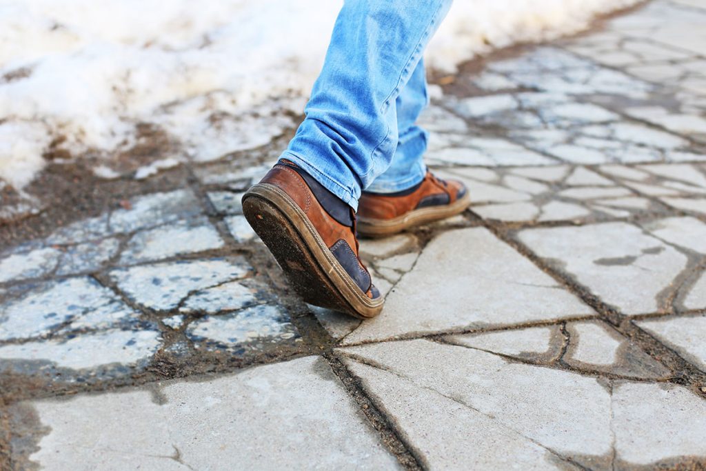Person walking on a broken, cracked sidewalk