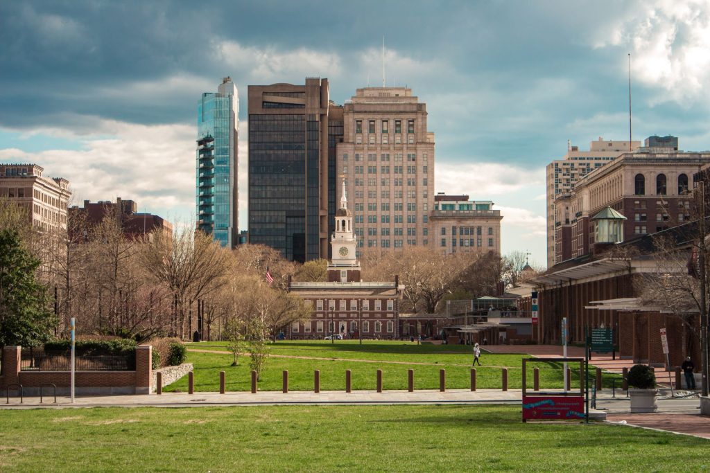 Independence Hall and green park space with the Philadelphia skyline in the background.