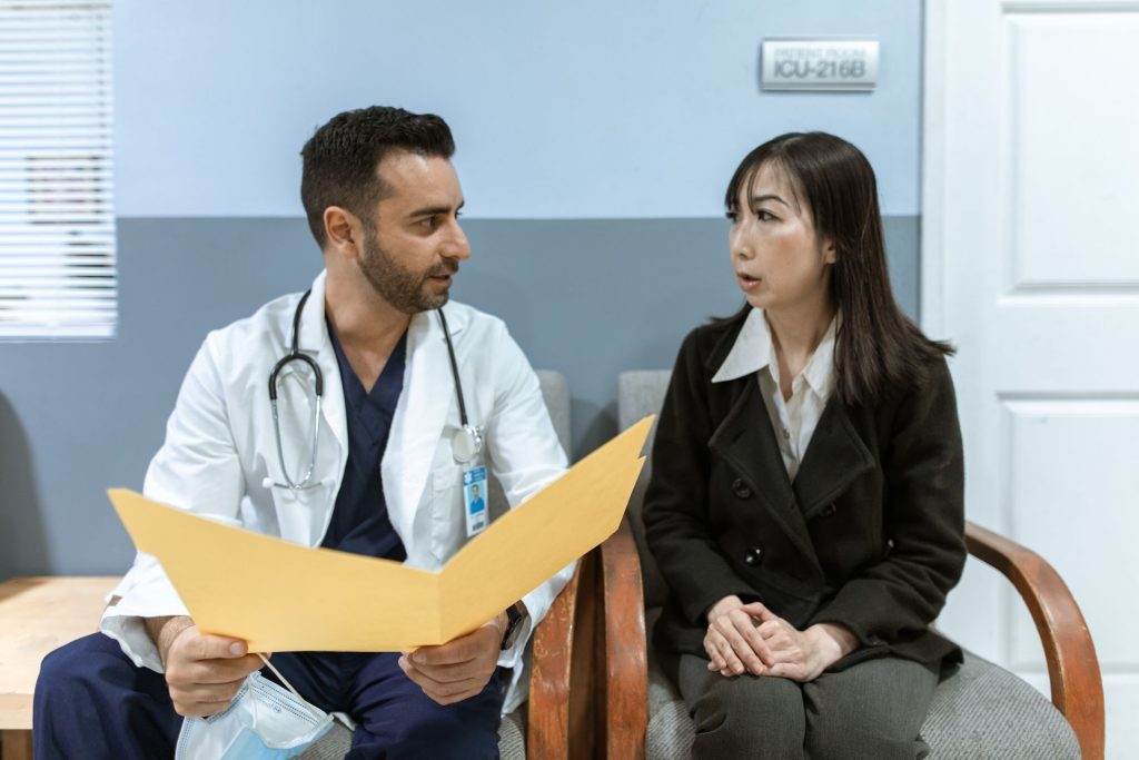 A male doctor consults with a female patient in a bright clinic setting following a personal injury accident.