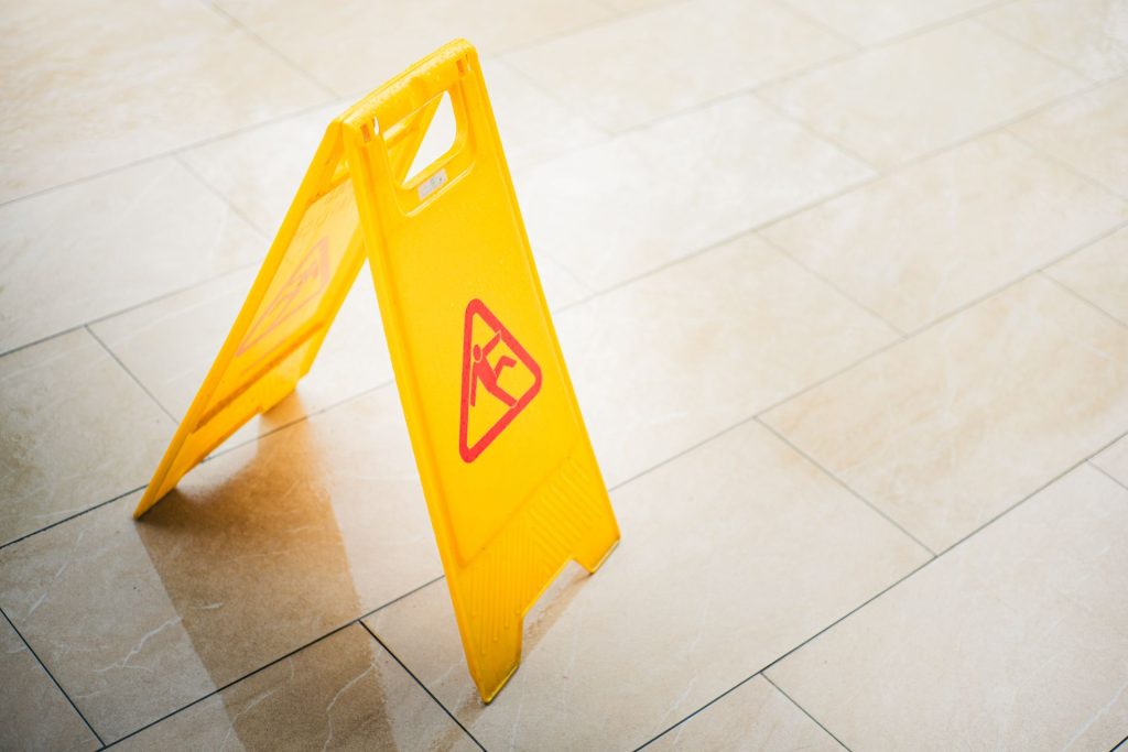 Yellow wet floor caution sign on tile flooring, representing a slip-and-fall hazard.