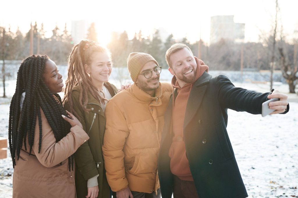 A group of friends taking a selfie together outdoors to post on social media